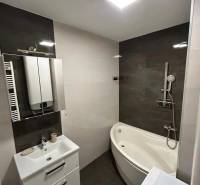 Bathroom with a shower, corner bathtub, sink, and tiles in a 3-room apartment.