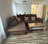 A comfortable living room with a brown sofa and a table, floor with wood decor.