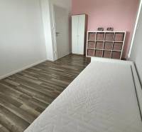 Bright room with a pink wall, bed, and dresser, wooden decor flooring.