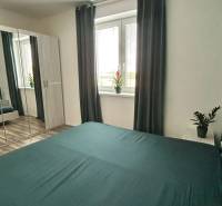 Bedroom in a 3-room apartment with a mirrored wardrobe, curtains, and a wooden decor floor.
