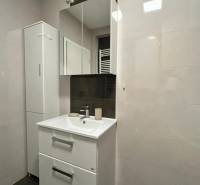 A bathroom in a 3-room apartment with white cabinets and a sink.