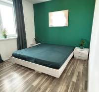 Bedroom in a 3-room apartment with a wooden decor floor; green wall, bed, window.