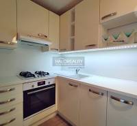 A kitchen in a 2-room apartment with white cabinets, a gas stove, and storage space.