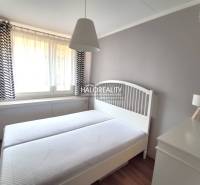 Bedroom in a two-room apartment with white furniture and light curtains.
