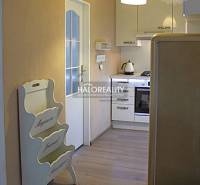 A kitchen in a 2-room apartment with a wooden decor floor and white appliances.