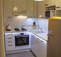 A kitchen in a 2-room apartment with white cabinets and a wood-patterned floor.