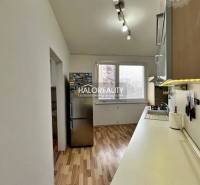 A kitchen in a 3-room apartment with a wooden decor floor and white walls.