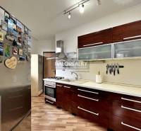 A kitchen in a 3-room apartment with a wood-patterned floor and appliances.