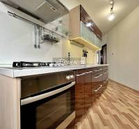 A kitchen in a 3-room apartment with a modern kitchen unit and a floor with a wooden decor.