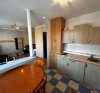 A kitchen with a dining table in a studio apartment, floor with wood decor.