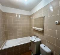 Bathroom with a bathtub, sink, toilet, and tiles in a studio apartment.