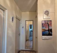 A hallway in a 2-room apartment with tiled flooring and a mirror on the wall.