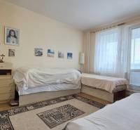 A room in a 2-room apartment with beds, a chest of drawers, and a floor with a wood decor.