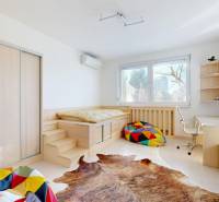 A room in a 5 or more bedroom apartment with a bed, colorful pillows, and a desk.