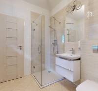A bathroom with a glass shower enclosure and beige tiles in a 5 or more room apartment.