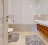 A bathroom in a five or more room apartment with a bathtub, sink, and tiles.