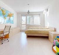A bright room in a 5 or more room apartment, wooden decor flooring, world map on the wall.