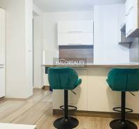 A kitchen in a 2-room apartment with turquoise chairs and a wooden decor floor.