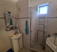 Bathroom in a family house, shower with a curtain, sink, mirror, and radiator.
