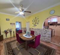 Dining room in a family house with a round table, chairs, and a wooden decor floor.