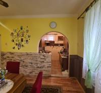 A dining room in a family house with an arched passage and a wooden decor floor.