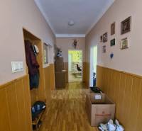 A hallway with a wooden decor floor, walls adorned with paintings in a family house.