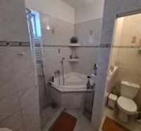 A bathroom in a family house with a bathtub and a separate toilet, tiled with light tiles.