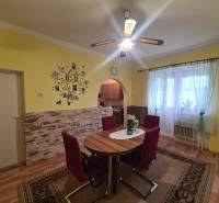 Dining room in a family house with a decorative wall, wood-patterned floor, and red chairs.