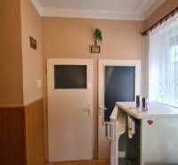 Interior of a family house with two doors, a refrigerator, and a wooden decor floor.