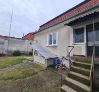 A family house in Hurbanovo with a terrace and garden, with fencing and trees in the background.