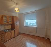 A kitchen with a wooden floor decor in a 3-room apartment with white walls and classic cabinets.