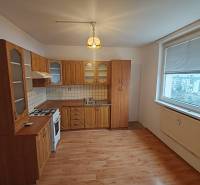A kitchen in a 3-room apartment with a wooden decor floor and a large window.