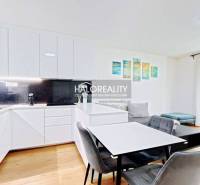 A kitchen in a 2-room apartment with white cabinets, a dining table, and a wooden decor floor.