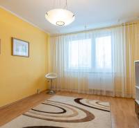 A room in a 4-room apartment with a wooden decor floor, yellow walls, and curtains.