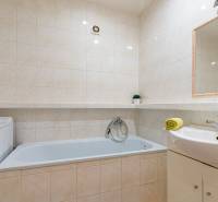 Bathroom in a 4-room apartment with a bathtub, washing machine, and sink with a towel.