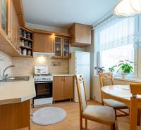 A kitchen in a 4-room apartment with a wooden decor floor, an island, and a dining nook.
