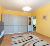 Interior of a 4-room apartment with a wooden decor floor, yellow walls, and furniture.