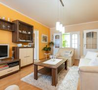 Living room in a 4-room apartment with a wooden decor floor and an orange wall.