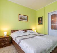 A bright bedroom in a 4-room apartment with paintings, a double bed, and lamps.