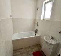 A bathroom in a family house with a bathtub, a sink, and a floor with a wooden design.