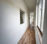 A hallway in a family house with a wooden decor floor and large windows.