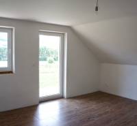 A bright room with windows, a wooden decor floor, and glass doors in a family house.