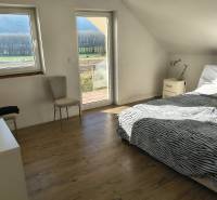 Bright bedroom in a family house with a bed, chair, and wooden decor flooring.