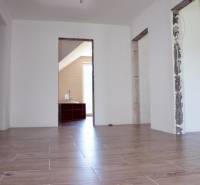 The interior of a family house with a wooden decor floor and uncovered construction openings.