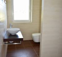 A bathroom in a family house with a light sink and a wooden decor floor.