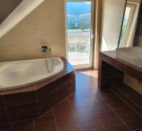 A family house bathroom with a bathtub and a wooden decor floor.