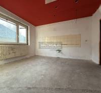 An empty room with a concrete floor in a family house with a red ceiling and a radiator.