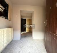 Entrance hallway of a family house with white tiles and brown doors.