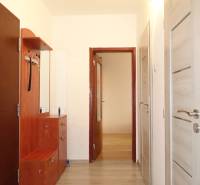 A hallway in a 3-room apartment with a wooden decor floor and light-colored furniture.