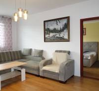 Living room in a 3-room apartment with a sofa, an armchair, and a wooden decor floor.